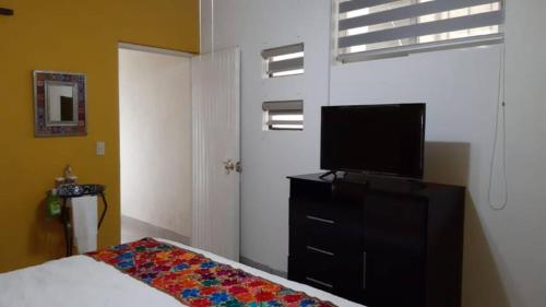 Dormitorio con cama y tocador con TV en departamento paraiso estrella Raquet Club, en San Juan Cosalá