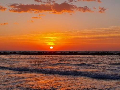 a sunset on a beach with the ocean at Alba sul Mare Guest House in Massignano
