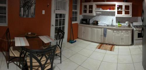 a kitchen with a table and chairs and a kitchen with orange walls at Tropical Apartments Tobago in Scarborough