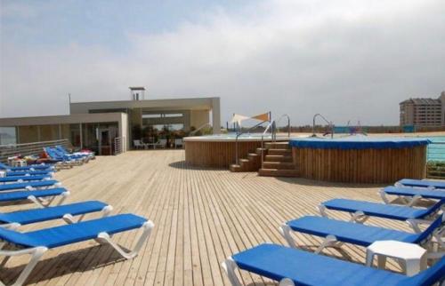 a group of blue lounge chairs sitting on a beach at DEPTO LAGUNA BAHIA MARINA in Algarrobo