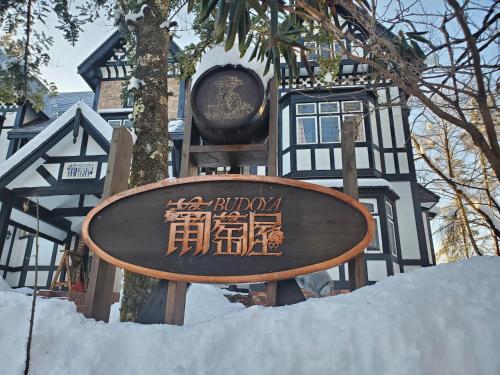 a sign in the snow in front of a building at プチホテル葡萄屋 in Hakuba