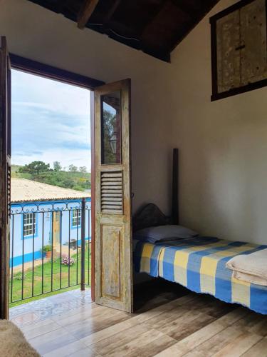 a bedroom with a bed and a door to a balcony at Recanto Bom Despacho in Tiradentes