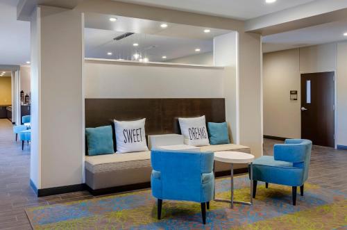 a waiting room with a couch and blue chairs at MainStay Suites Great Falls Airport in Great Falls
