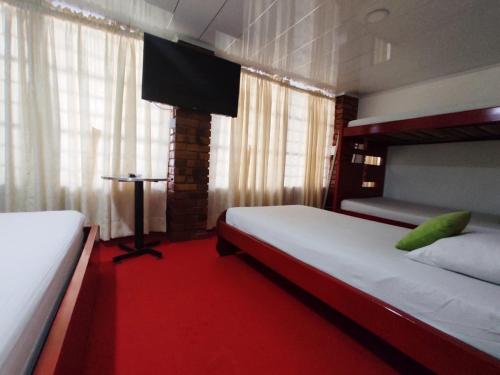 a bedroom with two beds and a red carpet at Hotel Casablanca Cañaveral in Floridablanca