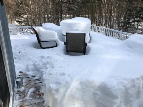 two chairs and a table in the snow at Chalets et Studios Le Vent Du Nord in Lac-Superieur