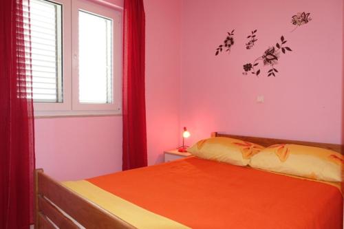 ein Schlafzimmer mit einem Bett mit orangefarbener Bettwäsche und einem Fenster in der Unterkunft Apartments Ivo - family friendly in Zaton