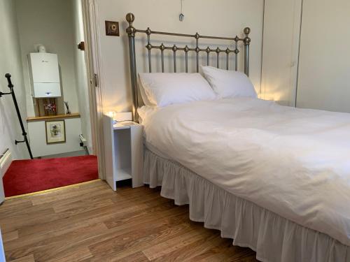 a bedroom with a bed with white sheets and a red rug at Charming Devon Cottage near Quay-Rain Shower, Restaurants & Free Parking in Kingsbridge