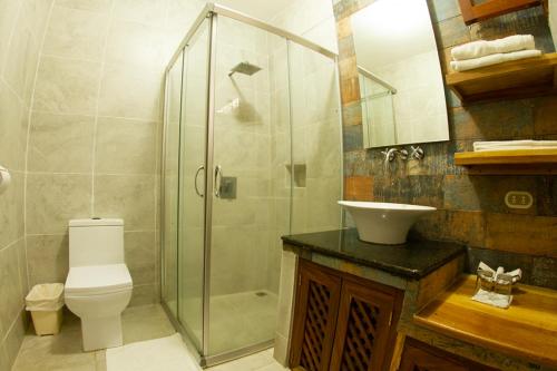 a bathroom with a shower and a toilet and a sink at Hotel Dos Mundos Panajachel in Panajachel