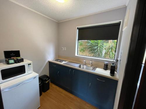 a small kitchen with a sink and a microwave at Hacienda Motor Lodge in Palmerston North