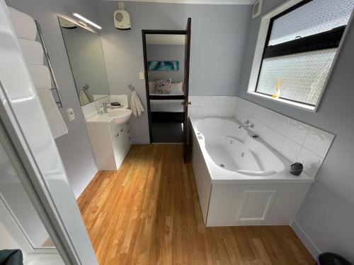 a white bathroom with a tub and a sink at Hacienda Motor Lodge in Palmerston North