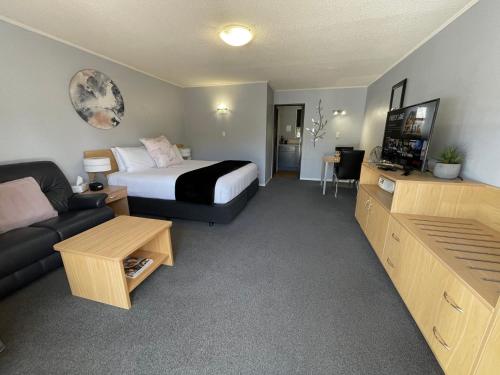 a hotel room with a bed and a couch at Hacienda Motor Lodge in Palmerston North