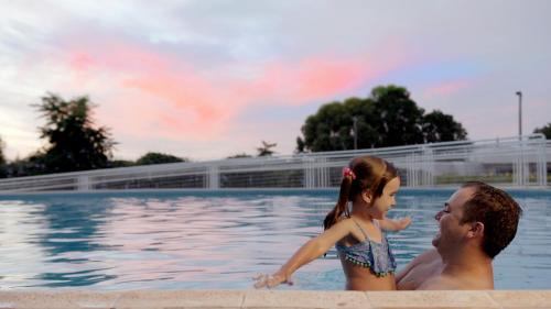 a man and a little girl in a swimming pool at Interludium Iguassu Convention Hotel in Foz do Iguaçu
