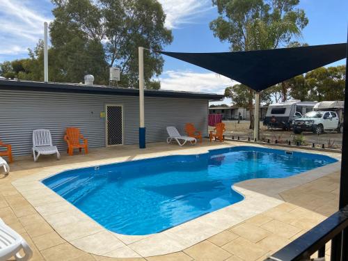 a swimming pool with a large umbrella on a patio at Broken Hill Tourist Park in Broken Hill