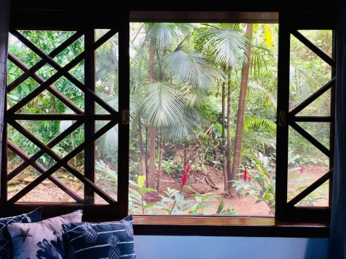 a window with a view of a palm tree at Casa Maresias Canto do mar - 50m da praia in Maresias