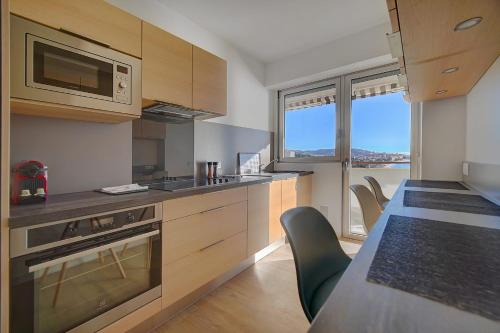 Il comprend une cuisine équipée d'un four micro-ondes et d'une table avec des chaises. dans l'établissement IMMOGROOM- Incredible View -4- Big Terrace - AC - Parking, à Cannes