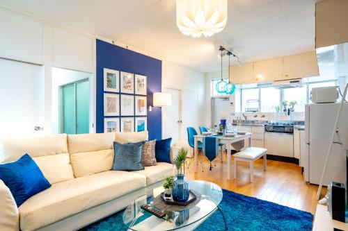 a living room with a white couch and a blue accent wall at Deluxe Room 130平米 URUMAHOTEL in Uruma