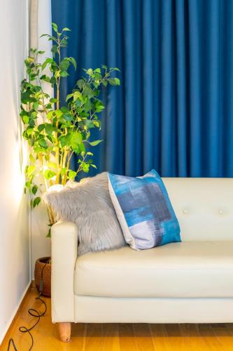 a white couch with a pillow and a plant at Deluxe Room 130平米 URUMAHOTEL in Uruma