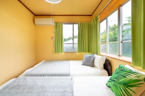 a bedroom with two beds and two windows at Deluxe Room 130平米 URUMAHOTEL in Uruma