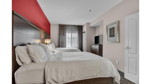 a hotel room with two beds and a red wall at Staybridge Suites Salt Lake-West Valley City by IHG in West Valley City