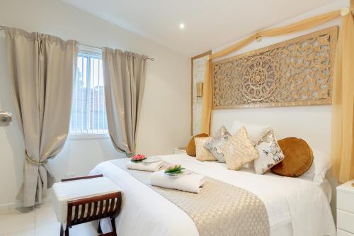 a white bedroom with two beds and a window at Sydney Executive Garden Apartments in Engadine