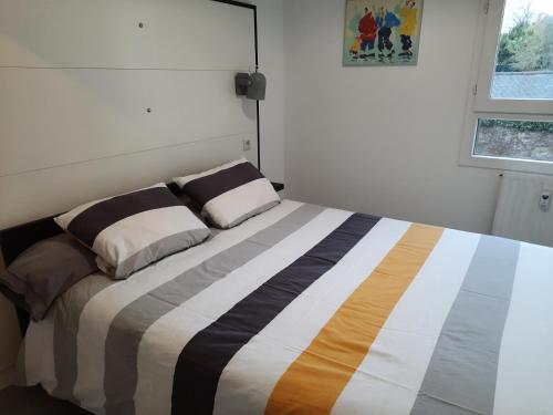 un lit avec deux oreillers dessus dans une chambre dans l'établissement La Poterie - Appartement avec balcon et parking privé, à Quimper