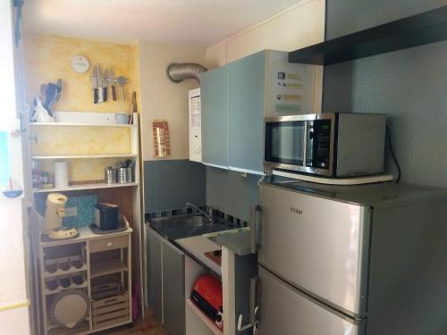 une petite cuisine avec un réfrigérateur et un micro-ondes dans l'établissement Charmant studio à Agde de 21 m² avec terrasse vue ville, au Cap d'Agde