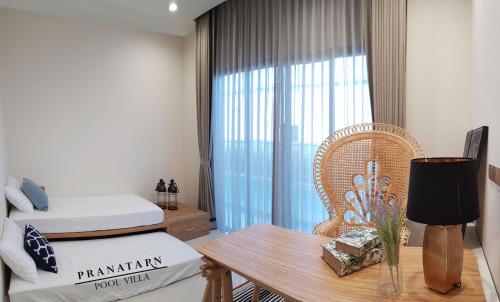 a bedroom with a bed and a table and a chair at Pranatarn Pool Villa Endless Summer in Pran Buri