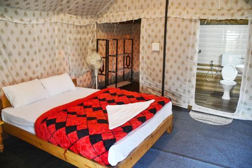 a bedroom with a bed and a bathroom with a toilet at Kodom Bari Retreat, Kaziranga in Kāziranga
