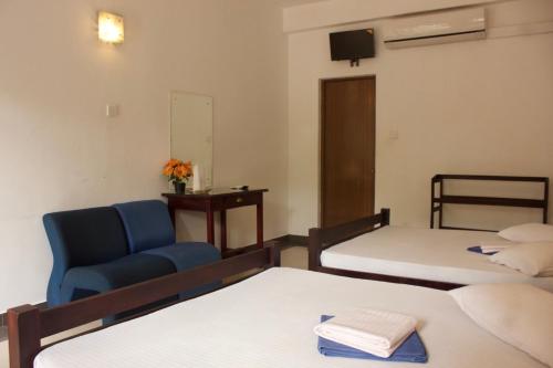 a room with two beds and a blue chair at Hotel Senora in Kataragama