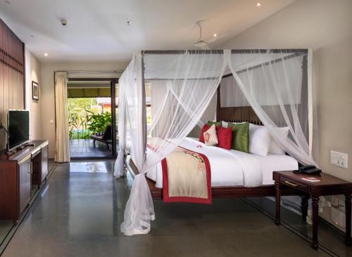 a bedroom with a bed with a canopy at Niraamaya Wellness Retreats Backwaters And Beyond Kumarakom in Kumarakom