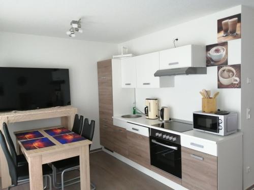 a kitchen with white cabinets and a table with a microwave at Strandläufer in Gelbensande