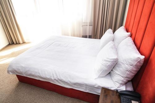 a bed with white pillows in a hotel room at International Bucharest City Centre Hotel in Bucharest