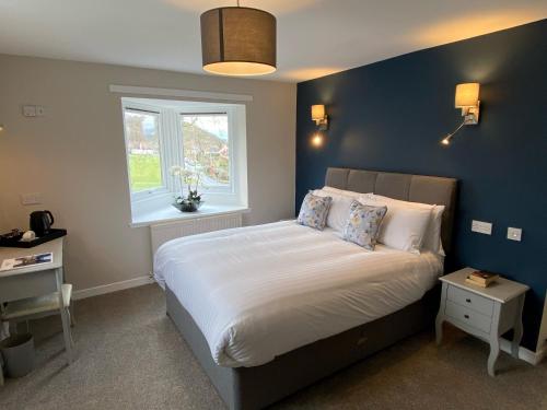 1 dormitorio con 1 cama grande y pared azul en The Inn At Charlestown en Dunfermline