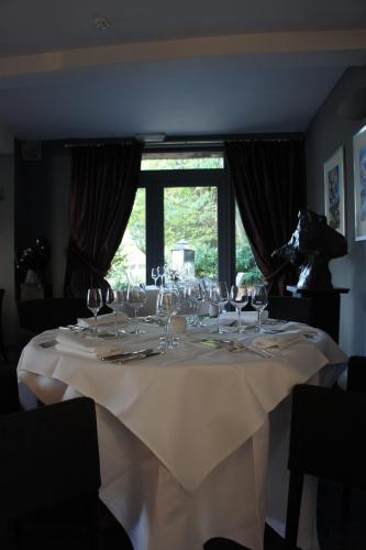 una mesa blanca con copas de vino encima en Orangerie de Blier à l'Affenage en Érezée