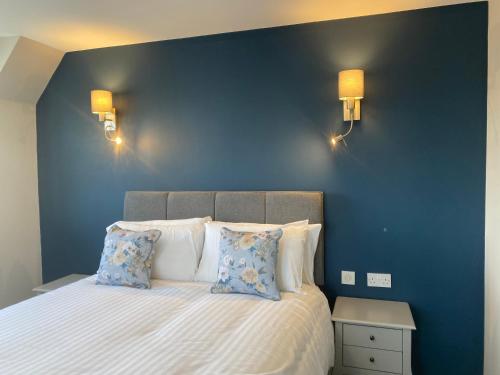 a bedroom with a blue wall and a bed with pillows at The Inn At Charlestown in Dunfermline