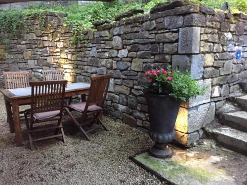einen Tisch, zwei Stühle und eine Steinmauer in der Unterkunft Orangerie de Blier à l'Affenage in Érezée
