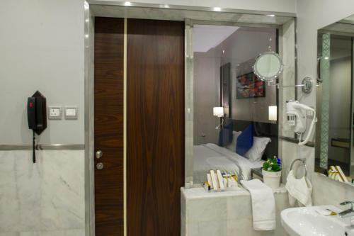 ein Bad mit einem Waschbecken, einem Bett und einem Spiegel in der Unterkunft Gorash Hotel in Chamis Muschait