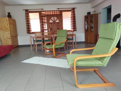 a dining room with green chairs and a table at Naszály Kapuja vendégház in Kosd