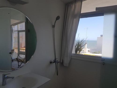 Un baño con espejo, lavabo y ventana. en Sentí el Mar.., en Punta del Este