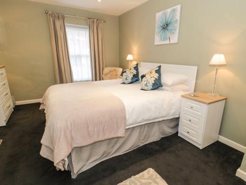 a bedroom with a large white bed with blue pillows at Cooper's Cottage in Morpeth
