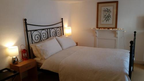 um quarto com uma grande cama branca e 2 candeeiros em Reed's of Fowey em Fowey