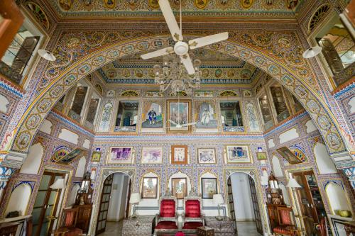 a large room with a ceiling fan and red chairs at Hotel Castle Mandawa in Mandāwa