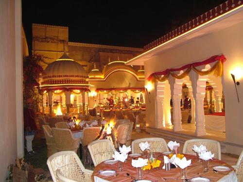 a restaurant with tables and chairs and a building at Hotel Castle Mandawa in Mandāwa