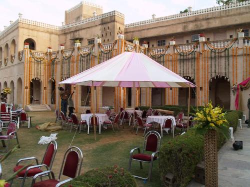 a patio with tables and chairs and a white umbrella at Hotel Castle Mandawa in Mandāwa