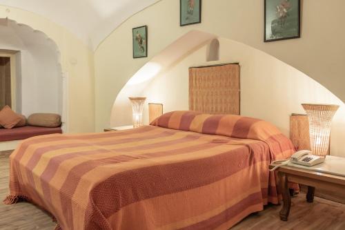a bedroom with a bed and a table with a phone at Hotel Castle Mandawa in Mandāwa