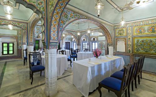 a dining room with tables and chairs and a wall mural at Hotel Castle Mandawa in Mandāwa