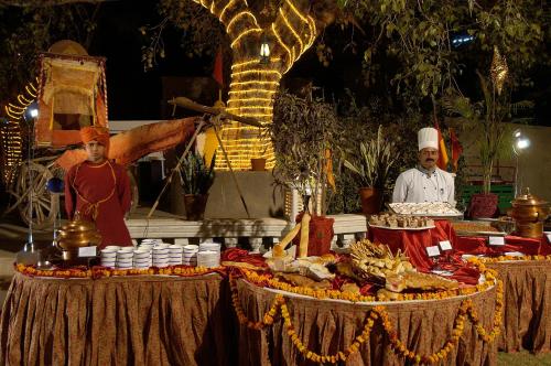 two men standing next to a table with food on it at Hotel Castle Mandawa in Mandāwa