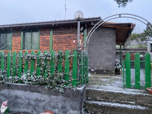 a house with a green fence in the snow at CHALET IL GELSOMINO DELL'ETNA in Giarre