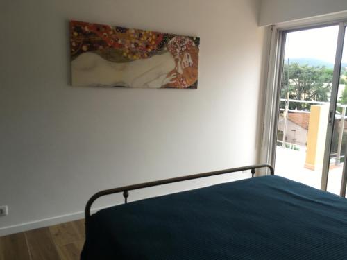 une chambre avec un lit et un tableau au mur dans l'établissement Appartement deux pièces , climatisé, terrase, Cavalaire, à Cavalaire-sur-Mer