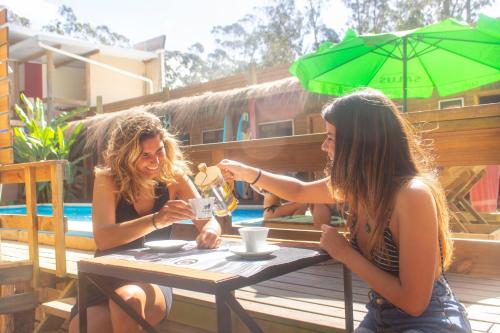 two women sitting at a table with a cup of coffee at Point Hostel in La Pedrera